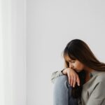 Woman sitting alone in a quiet space, reflecting emotionally