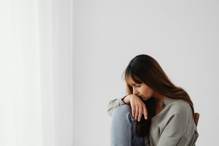 Woman sitting alone in a quiet space, reflecting emotionally