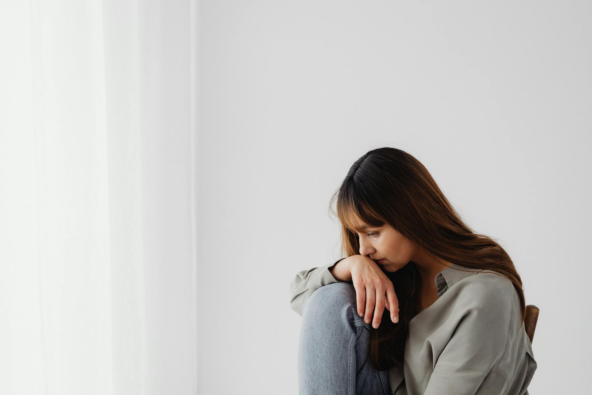 Woman sitting alone in a quiet space, reflecting emotionally
