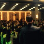 A speaker stands on stage addressing a crowd during an awards ceremony