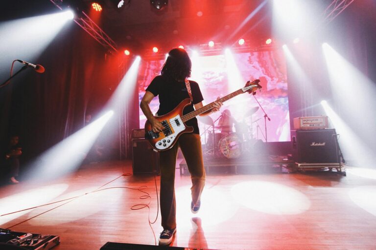 Guitarist performing on stage with dramatic red stage lighting and Marshall amplifiers
