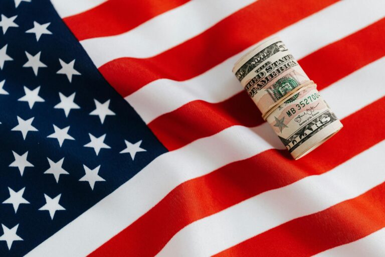 Roll of US dollar bills on American flag representing economy and financial policy