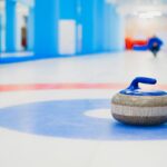 Curling stone resting on ice at the house representing the double-touch controversy from the 2026 Winter Olympics