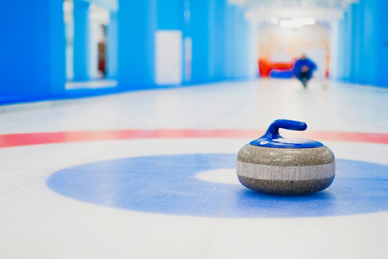 Curling stone resting on ice at the house representing the double-touch controversy from the 2026 Winter Olympics