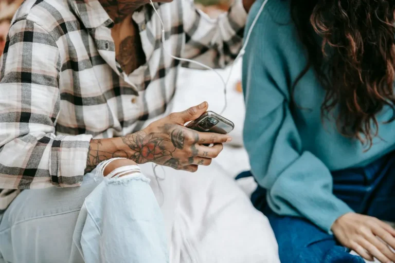 Two people sitting together looking at smartphones