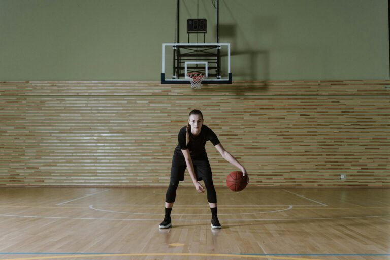 Woman dribbling a basketball alone on an empty court reflecting the individual vs collective tension in WNBA labor negotiations